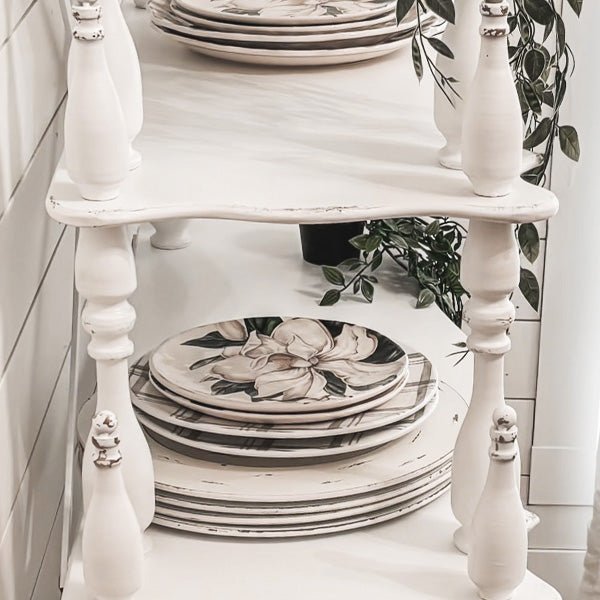 Lower tier of distressed white etagere with turned legs and open shelf space
