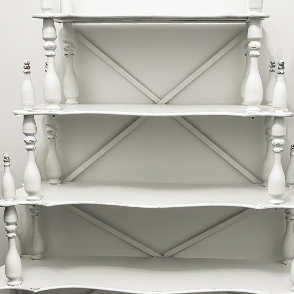 Back view of distressed white etagere showing X-shaped support panels on shelves