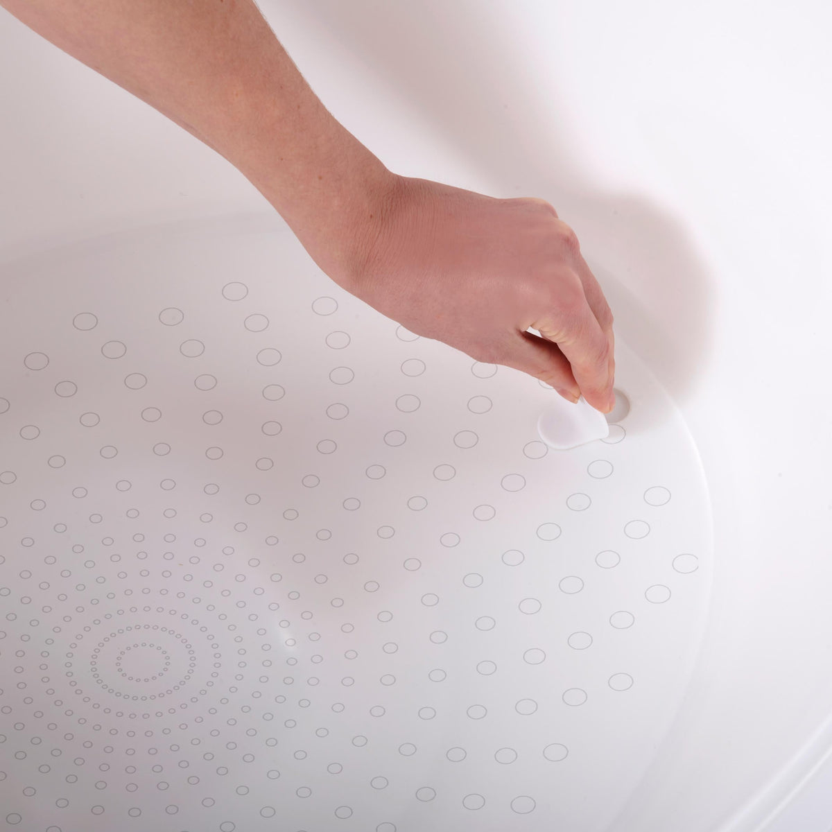 Anti-slip texture on white toddler bath tub base, hand smoothing the surface