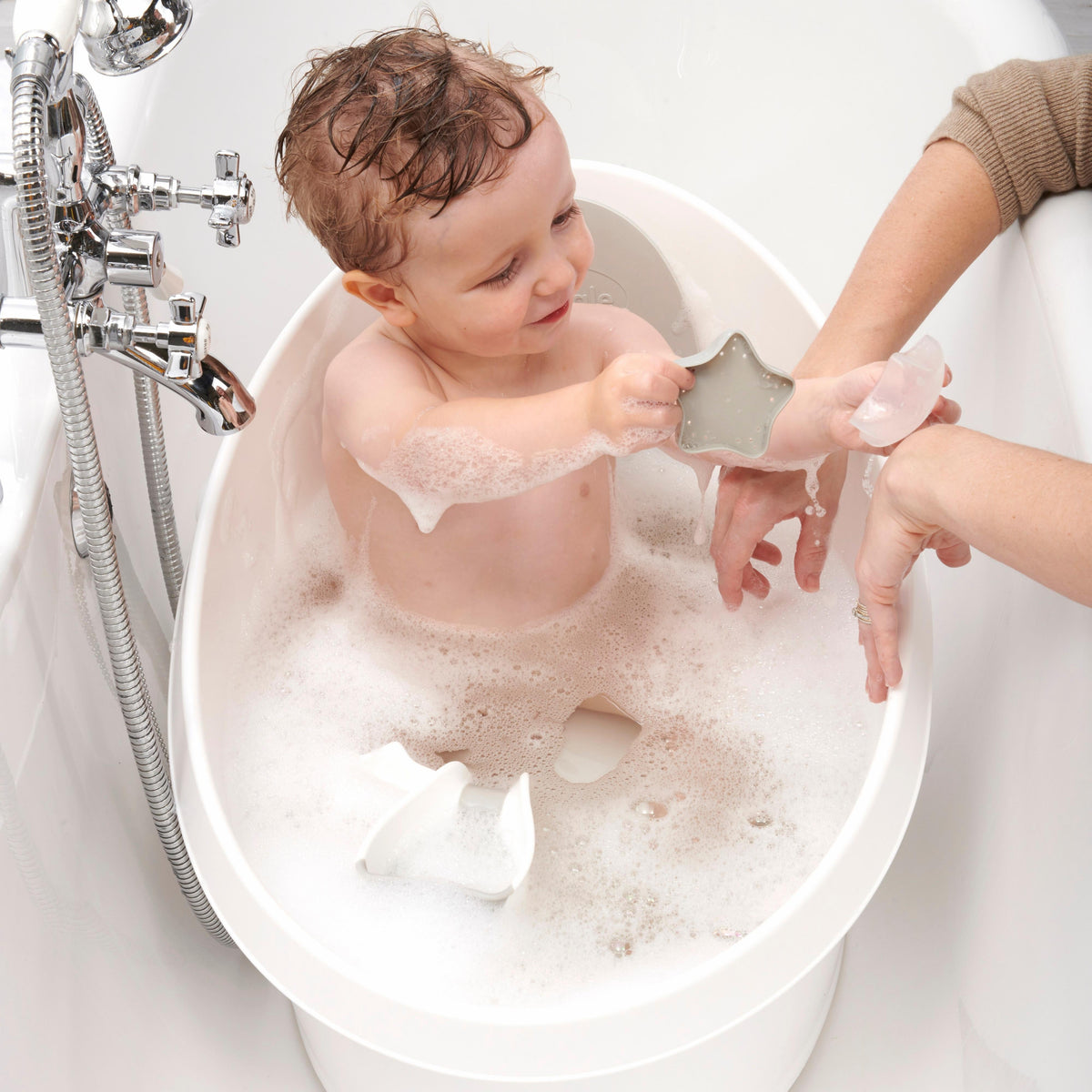 Toddler bath tub with white backrest, child rinsed with handheld shower