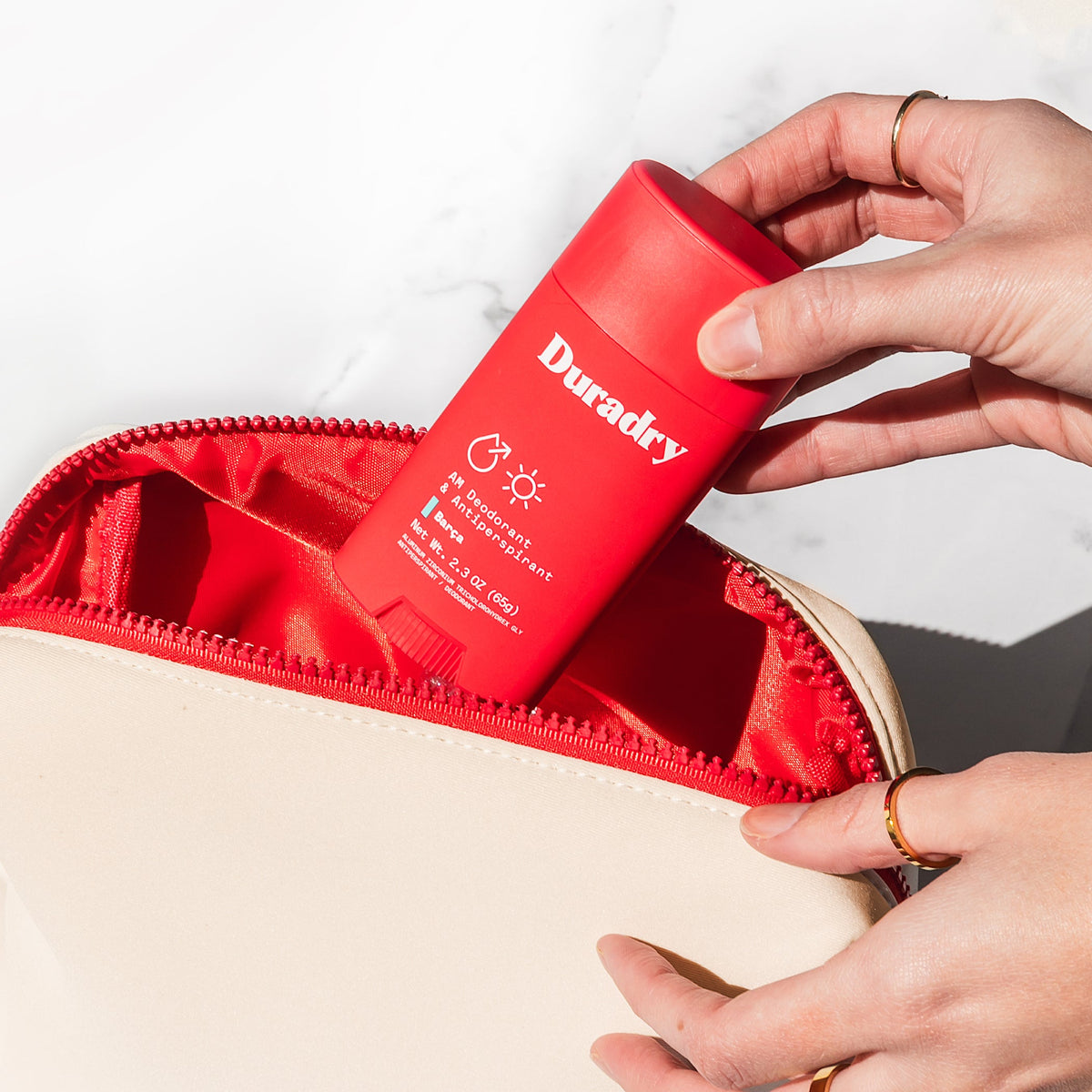 Cream bag opening with red Duradry spray bottle applied inside zipper compartment.