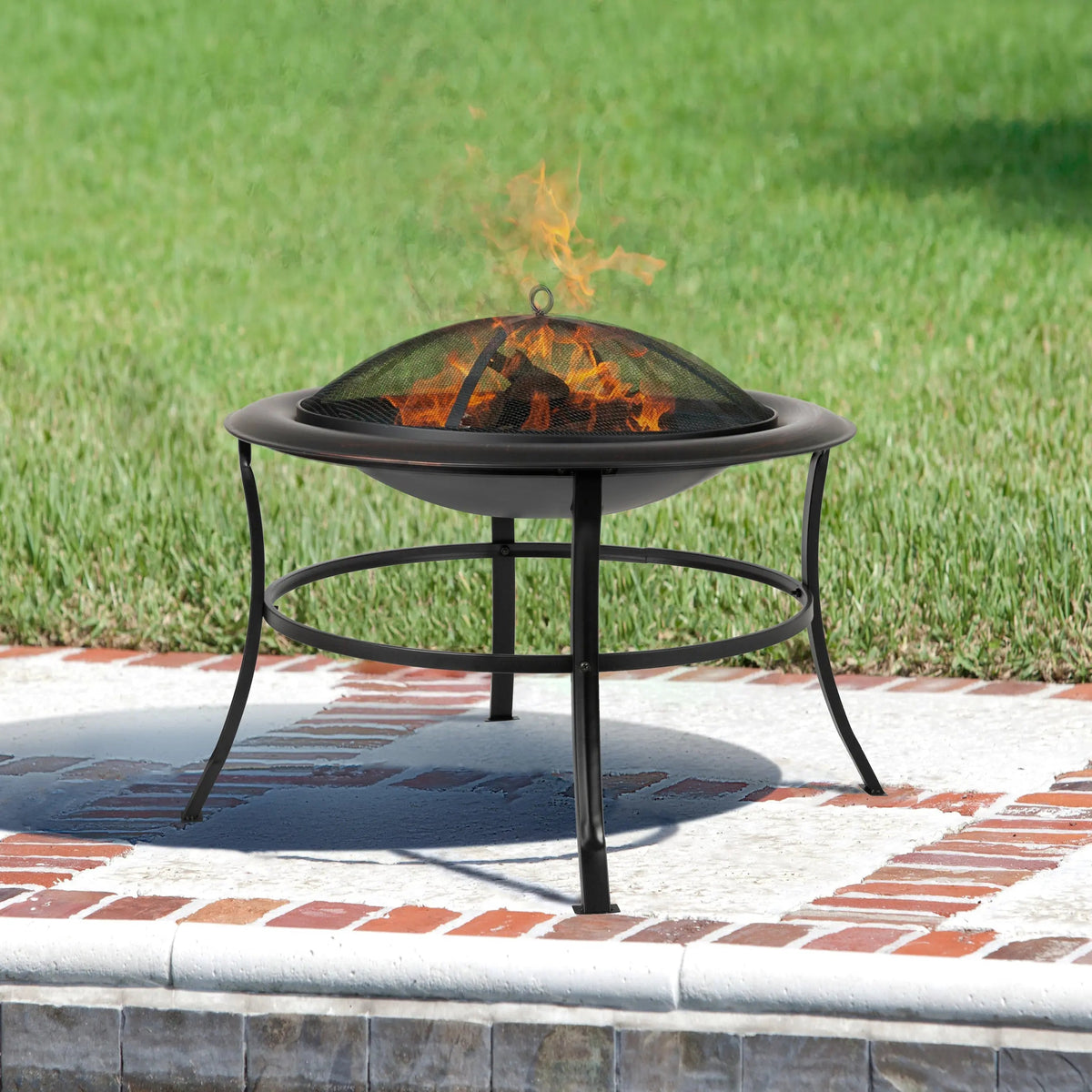 Outdoor round fire pit with raised grate and mesh spark screen, burning flames