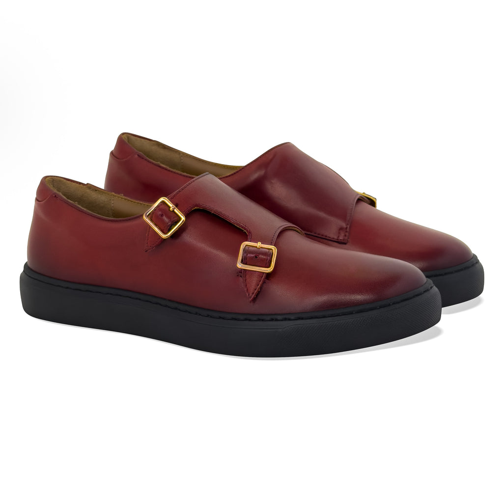 Women’s dark red slip-on shoes with twin straps, gold buckles, and black platform sole