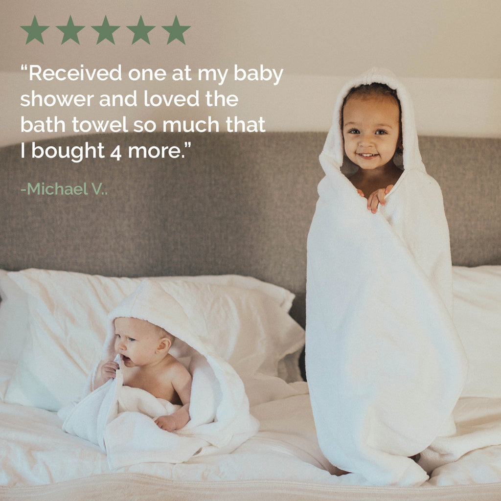 White hooded bath towel with a baby wrapped in the hood on a bed
