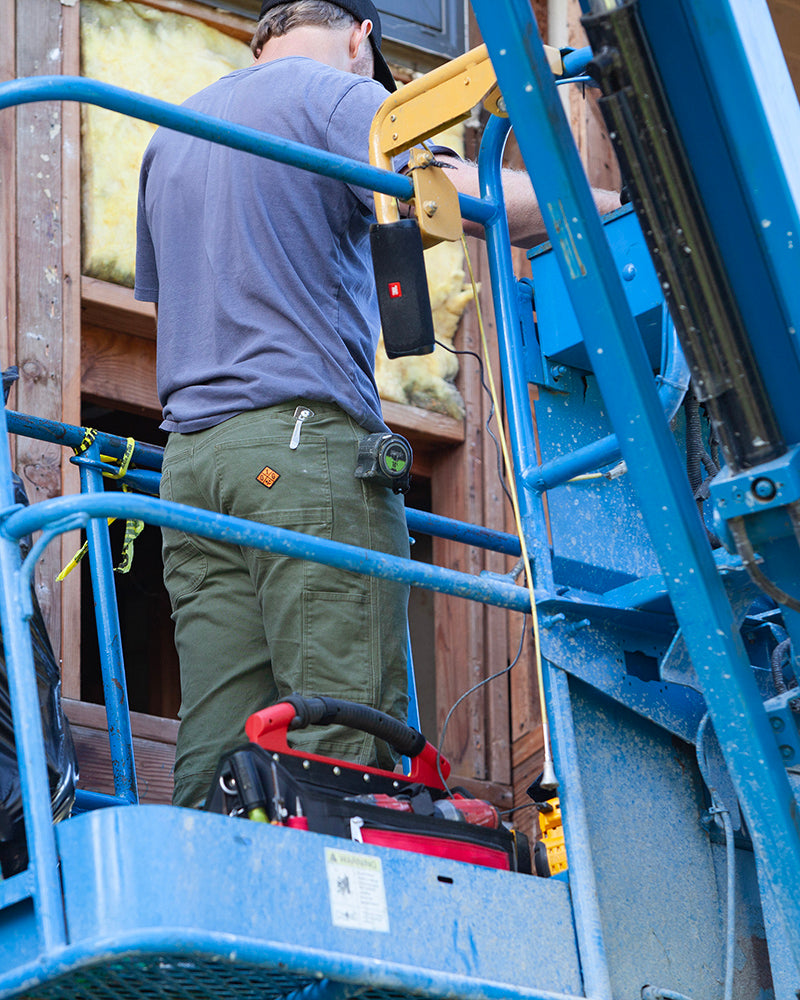 Men's olive taper-fit pants with belt loops and side pockets on a worker