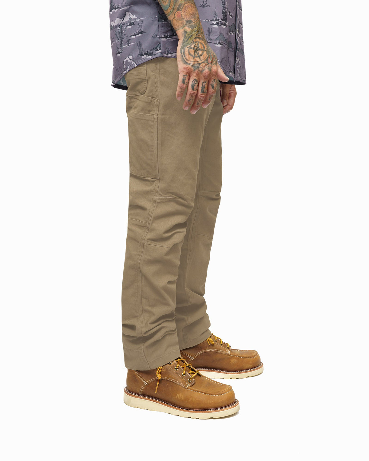 Coyote tan pants with side pocket detail and front fly seam; worn with boots