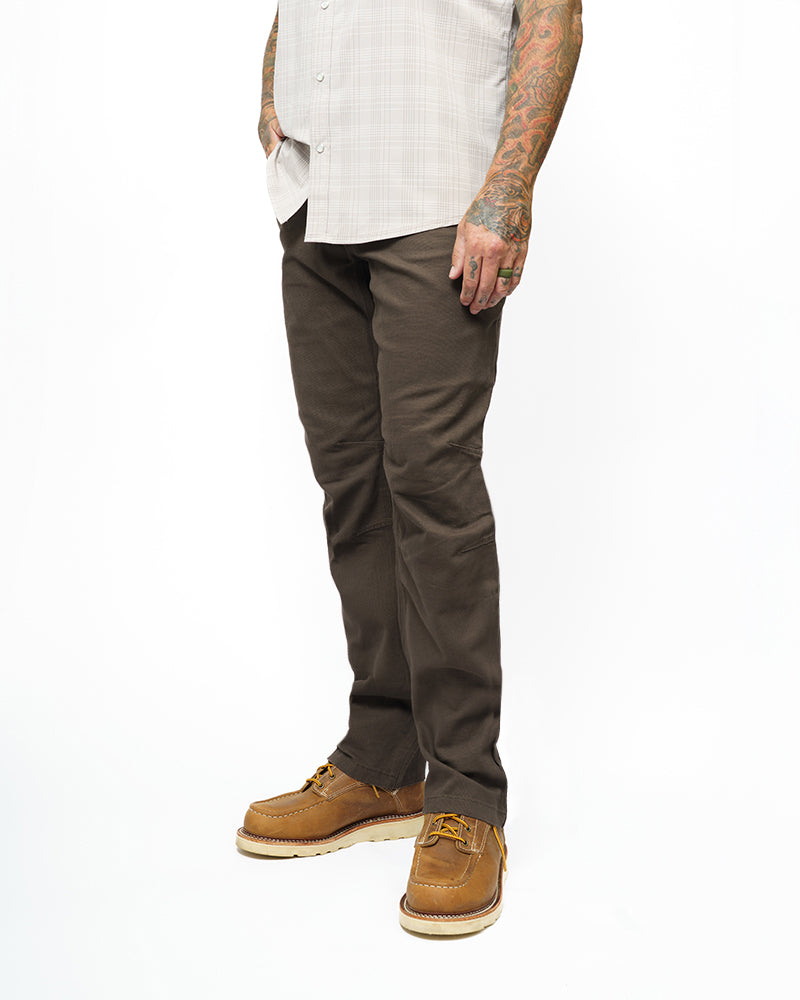 Dark brown taper-fit pants with front pockets and belt loops, worn with boots.