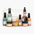 Travel-size skincare bundle with assorted facial oils, toner, serum, and creams in bottles