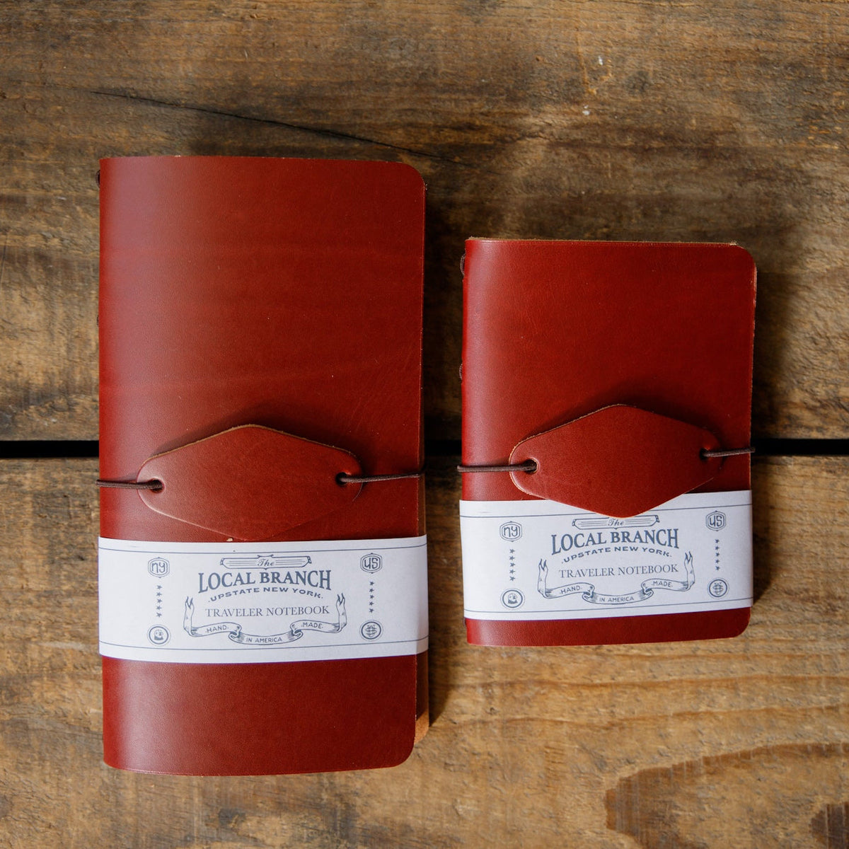 Red leather traveler notebooks with strap closure and Local Branch label, top view