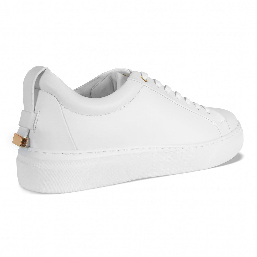 White low-top sneakers with gold lace tips, lace-up front, and padded collar
