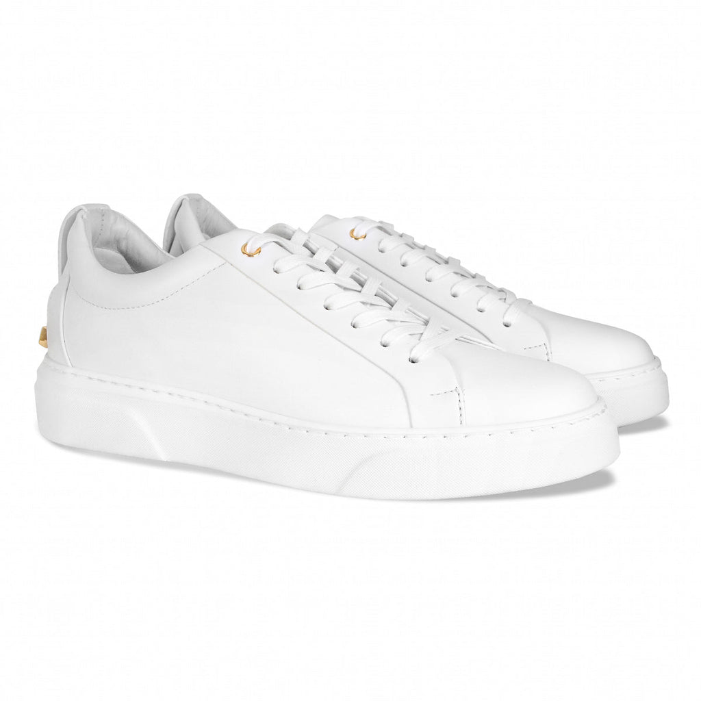 Pair of white low-top sneakers with white laces and gold-accent eyelets