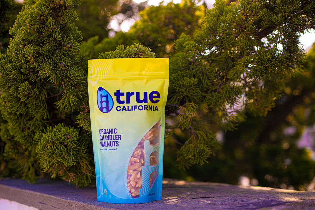 Stand-up bag of organic walnuts in front of green tree branches