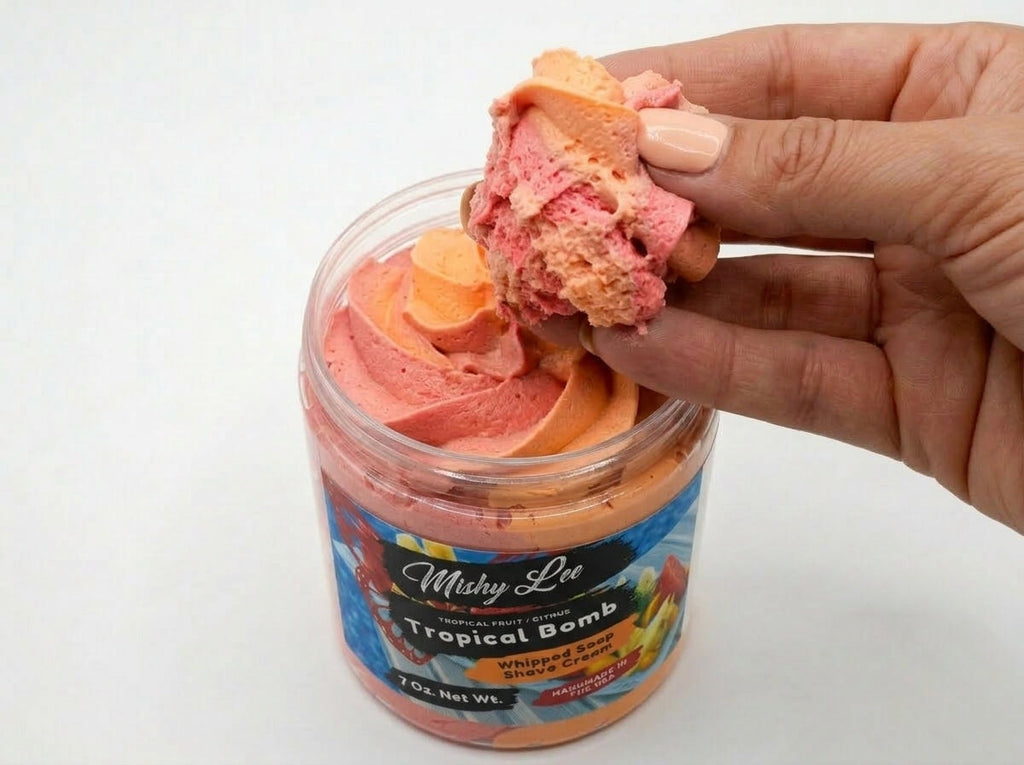 Hand holding a scoop of pink and orange whipped soap from the Tropical Bomb jar