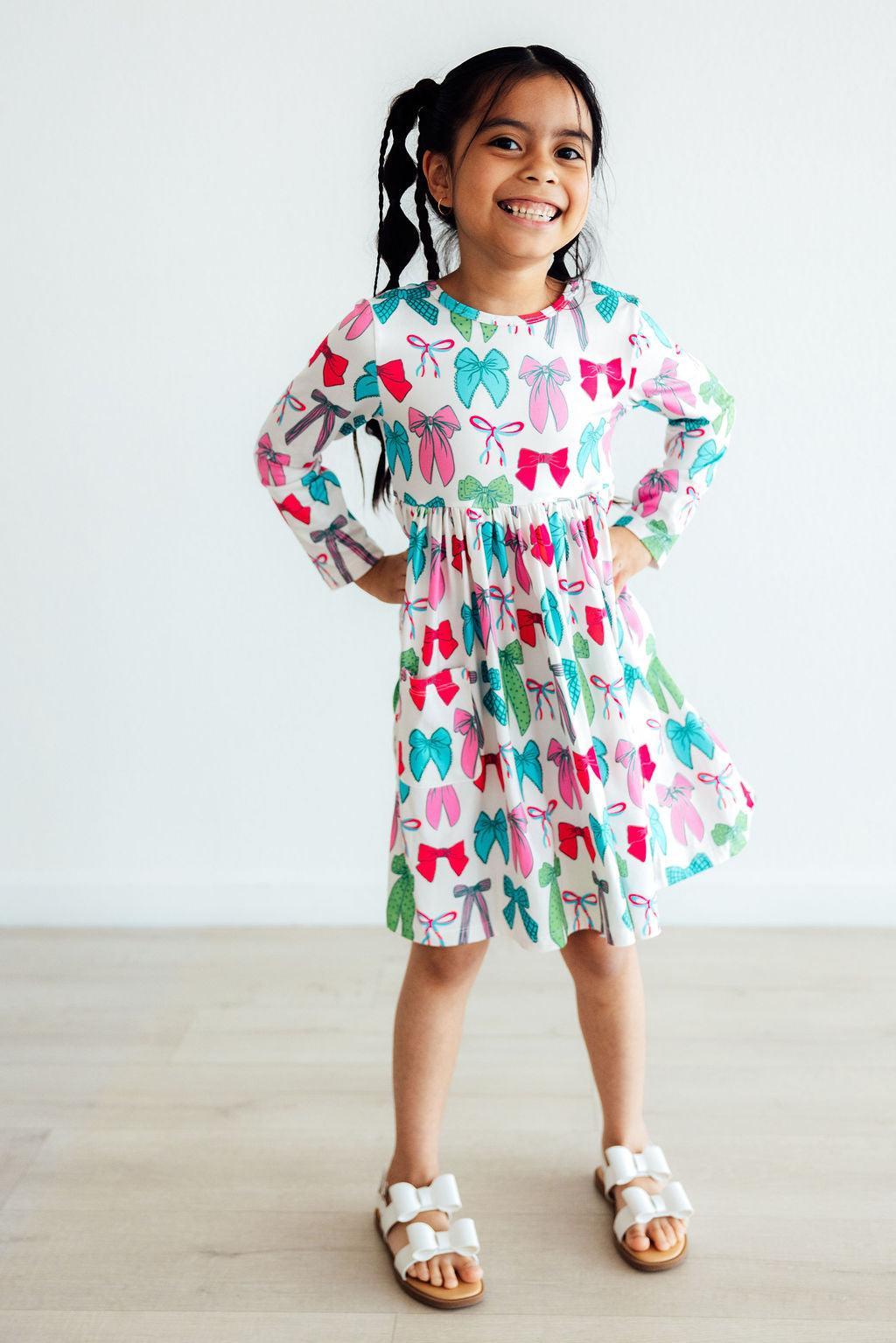 Girls long-sleeve twirl dress with colorful bow print, tiered design and flared skirt