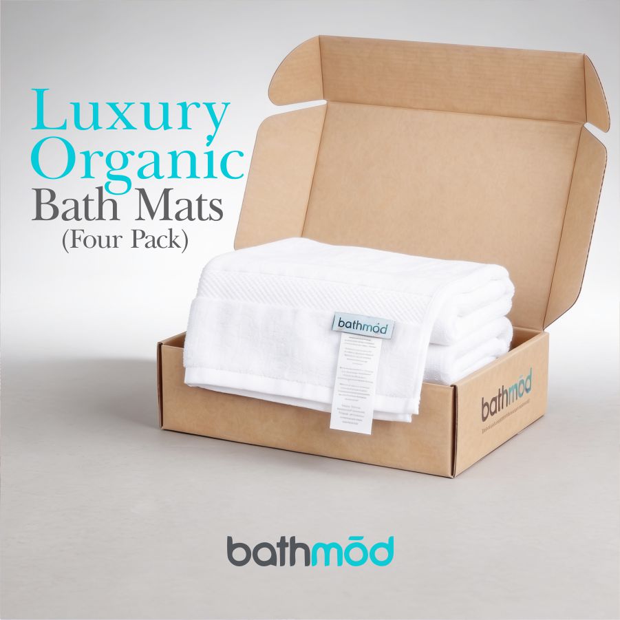 Folded white bath mats in an open cardboard box, Bathmood four-pack