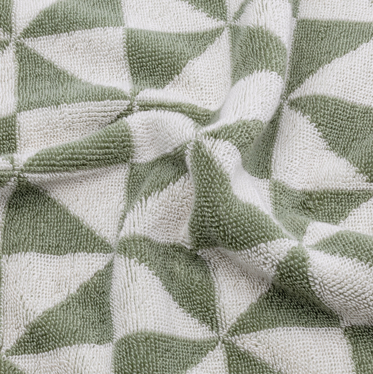 Close-up of sage and ecru geometric cotton towel weave with textured terry loops.