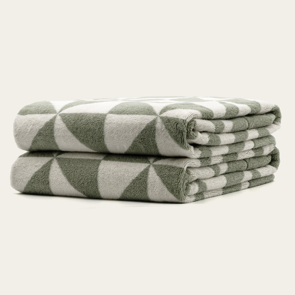 Sage and ecru geometric cotton towels, folded stack with corner detail and terry texture.