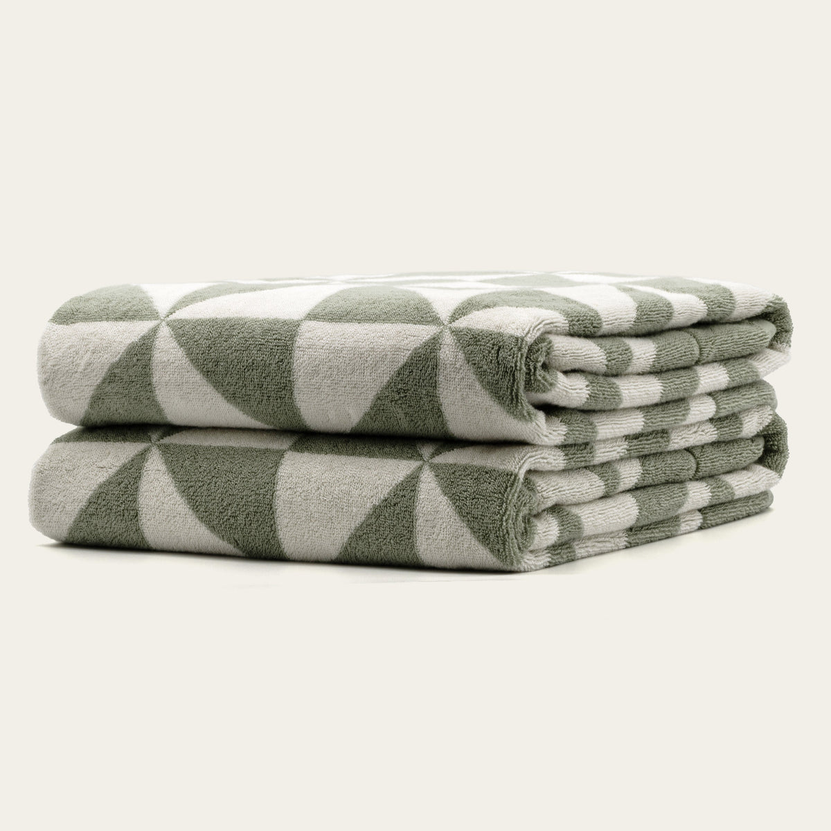 Sage and ecru geometric cotton towels, folded stack with corner detail and terry texture.