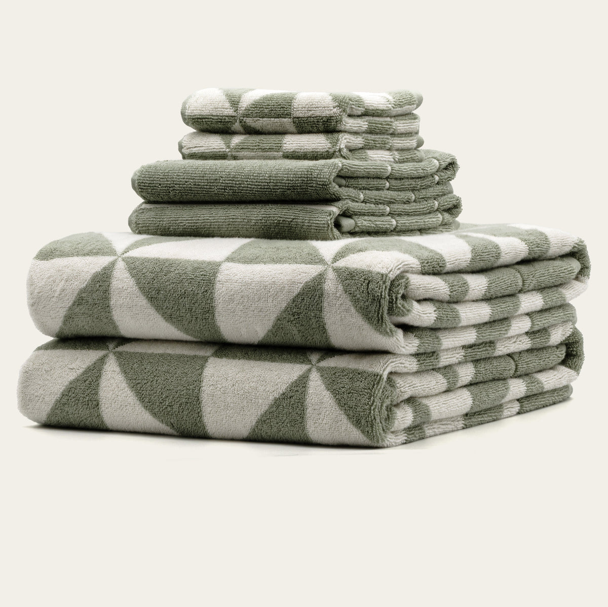 Stack of sage and ecru geometric cotton towels with folded rolled edges