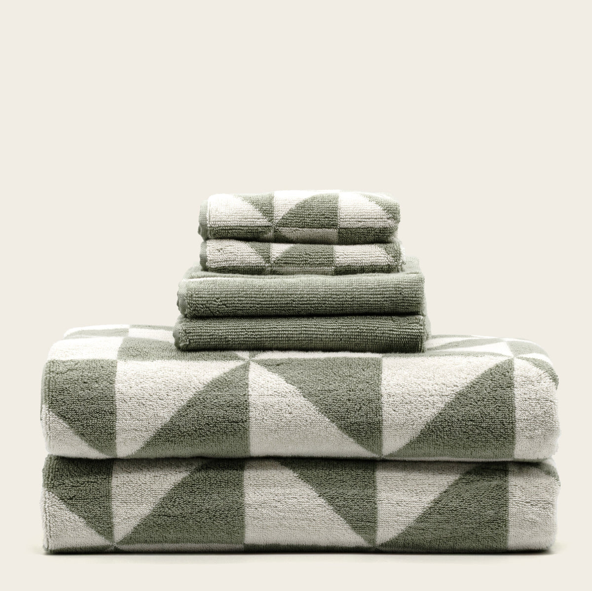 Folded cotton towels with sage green and ecru geometric pattern on top towel