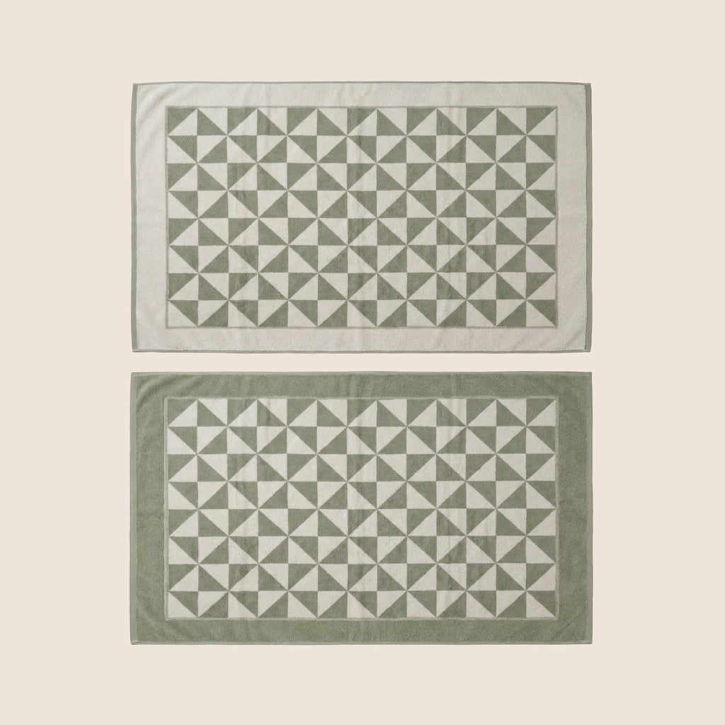 Two folded cotton towels with geometric triangle border, sage green and ecru