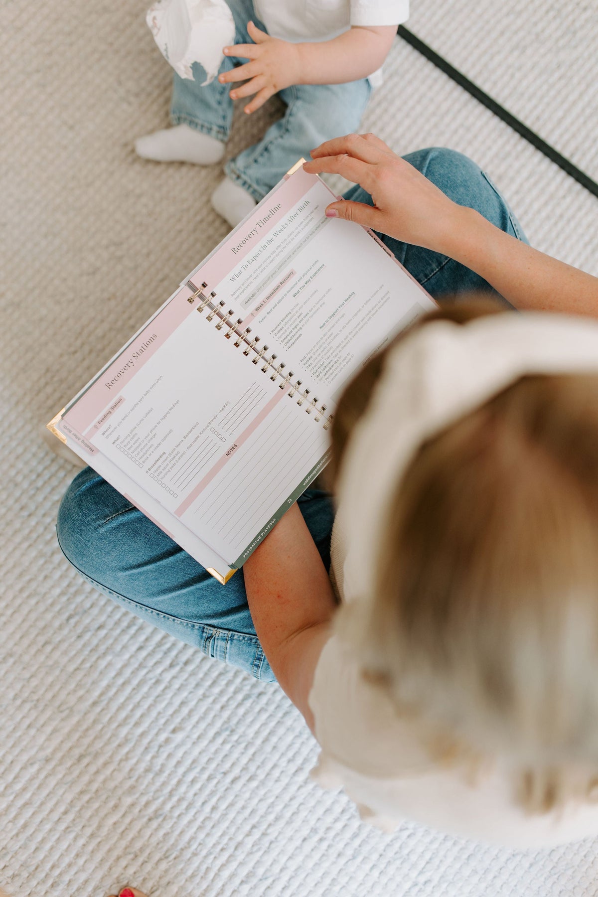 Postpartum planner guide, open pages with spiral binding, pink and white cover
