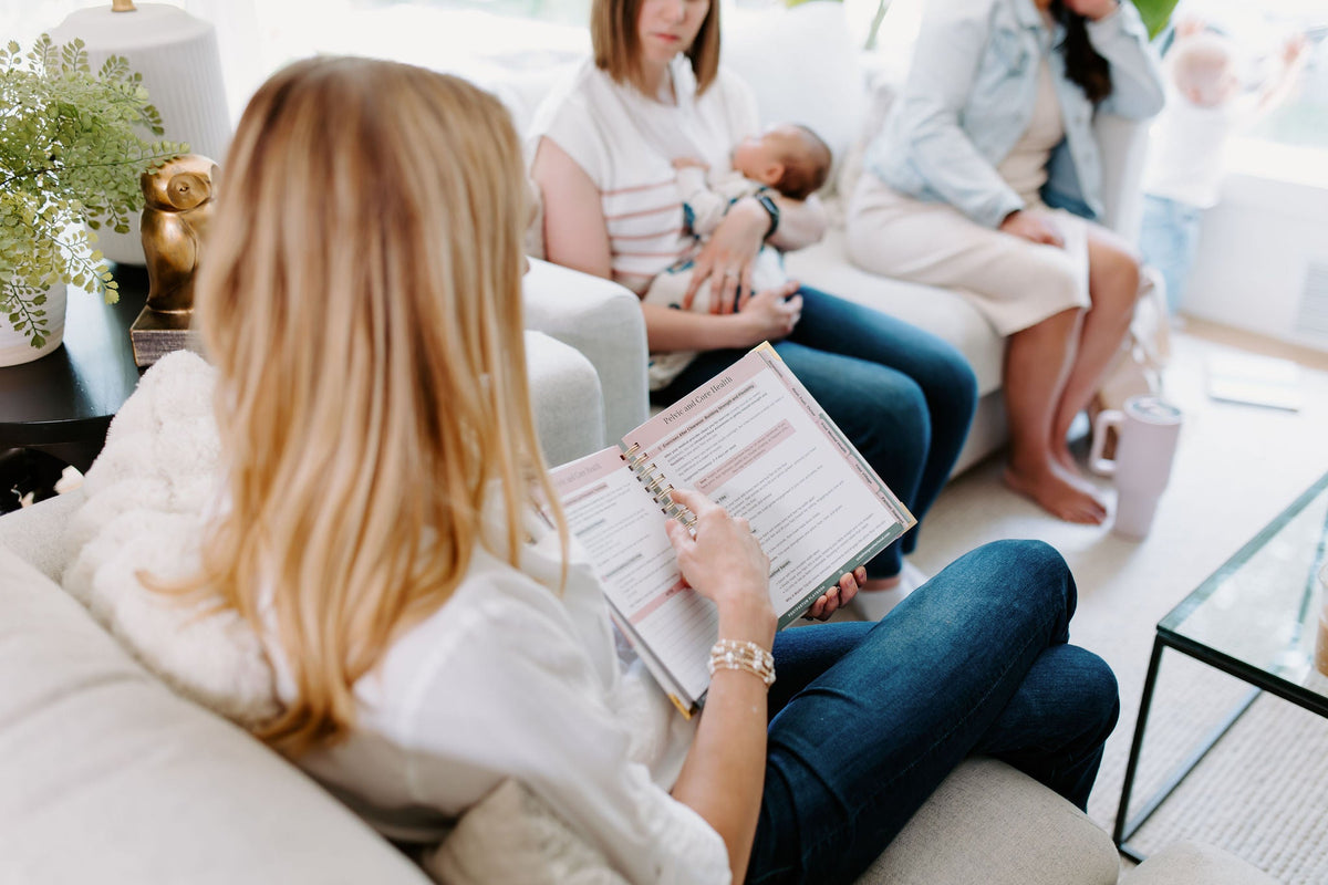 Postpartum planner guide open in a seat as someone fills in the printed sections