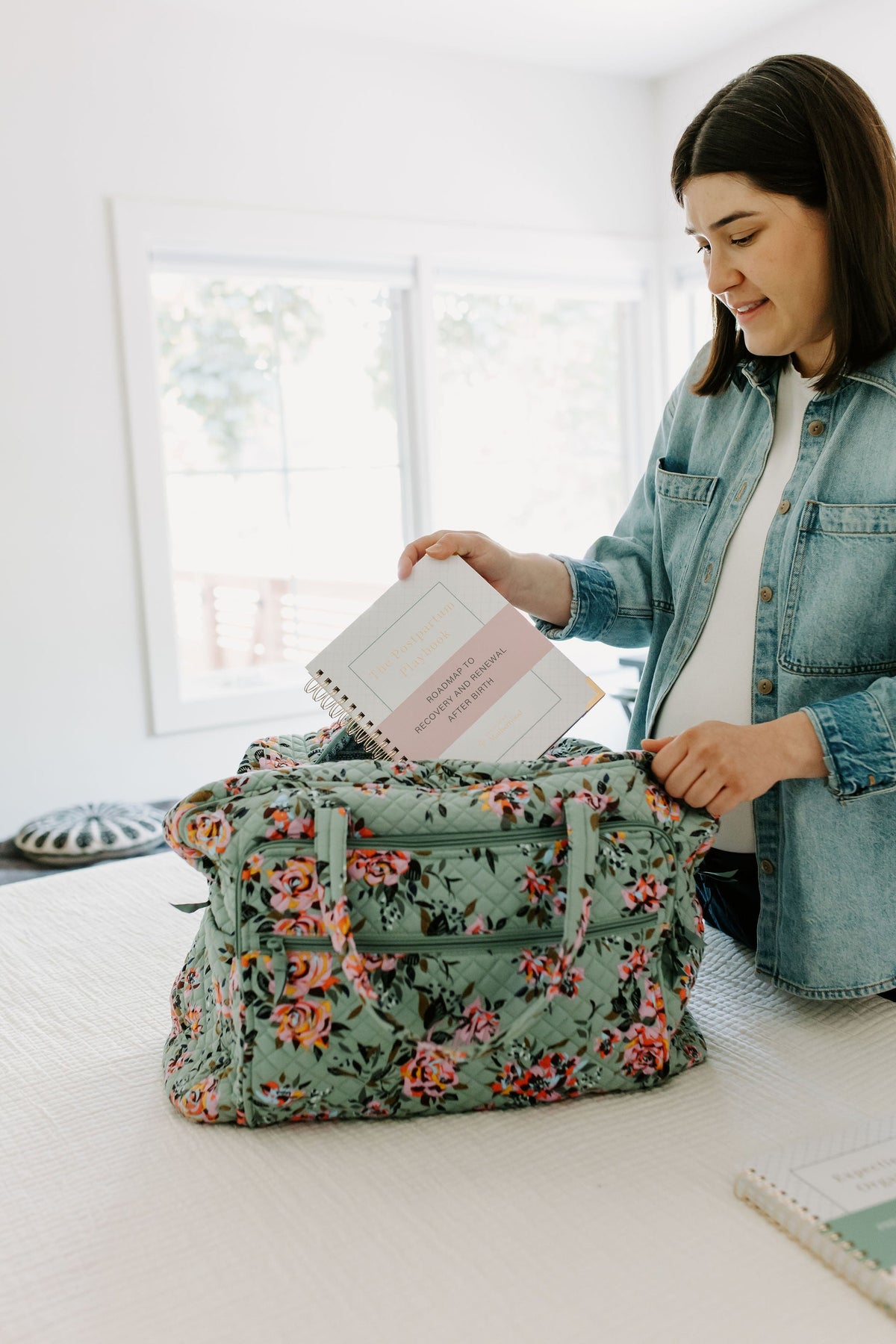 Postpartum planner guide open as someone prepares a floral fabric bundle