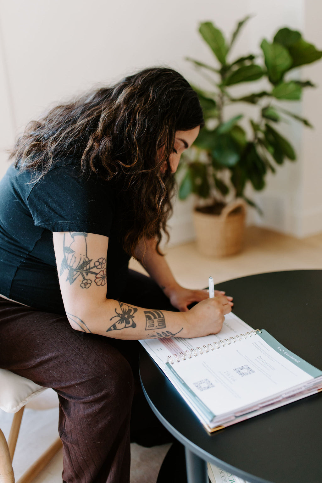 Postpartum planner guide open on a desk while someone writes with a pen