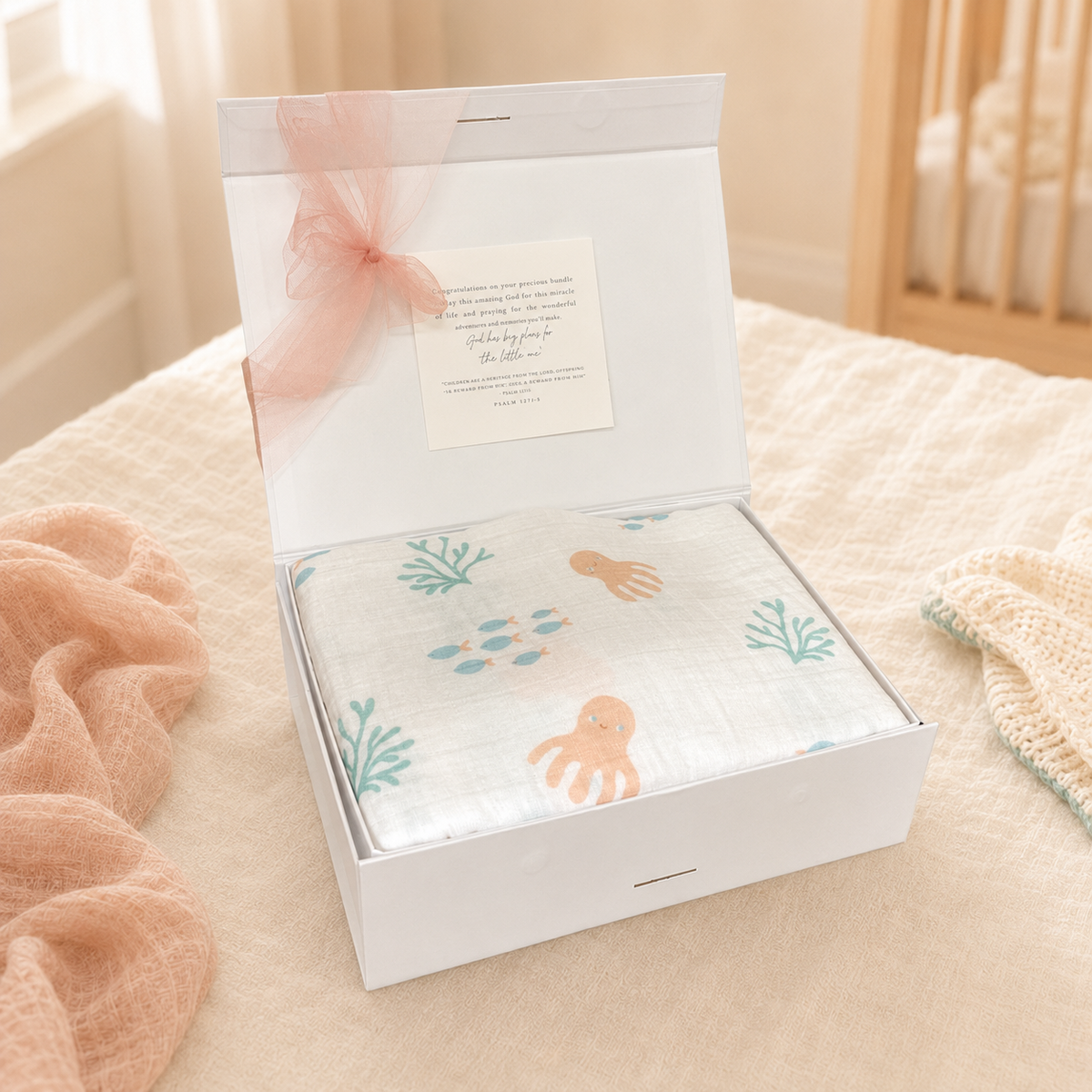 Under-the-sea muslin swaddle blanket with sea-creature print, folded in gift box