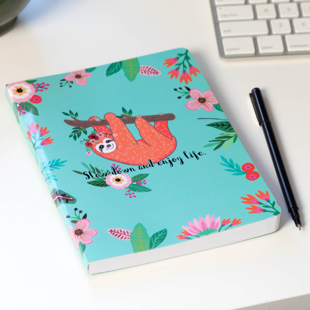 Teal notebook journal with sloth cover design and pen beside it