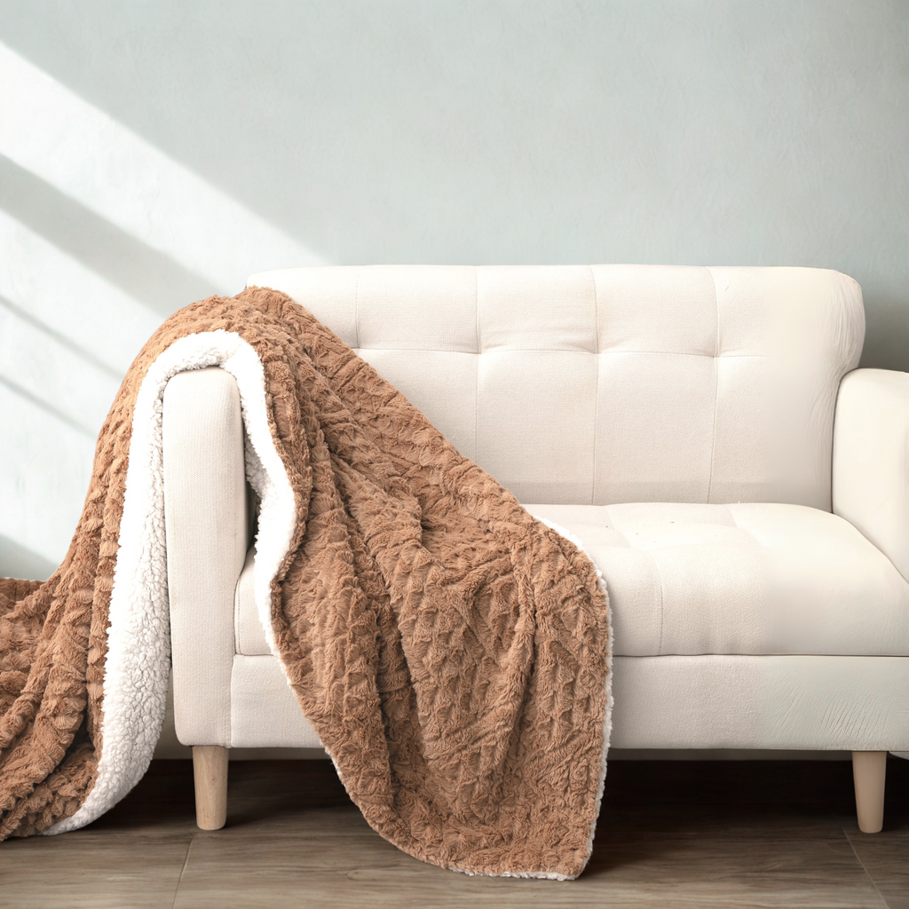 Caramel brown faux fur throw blanket with cream sherpa lining draped over sofa