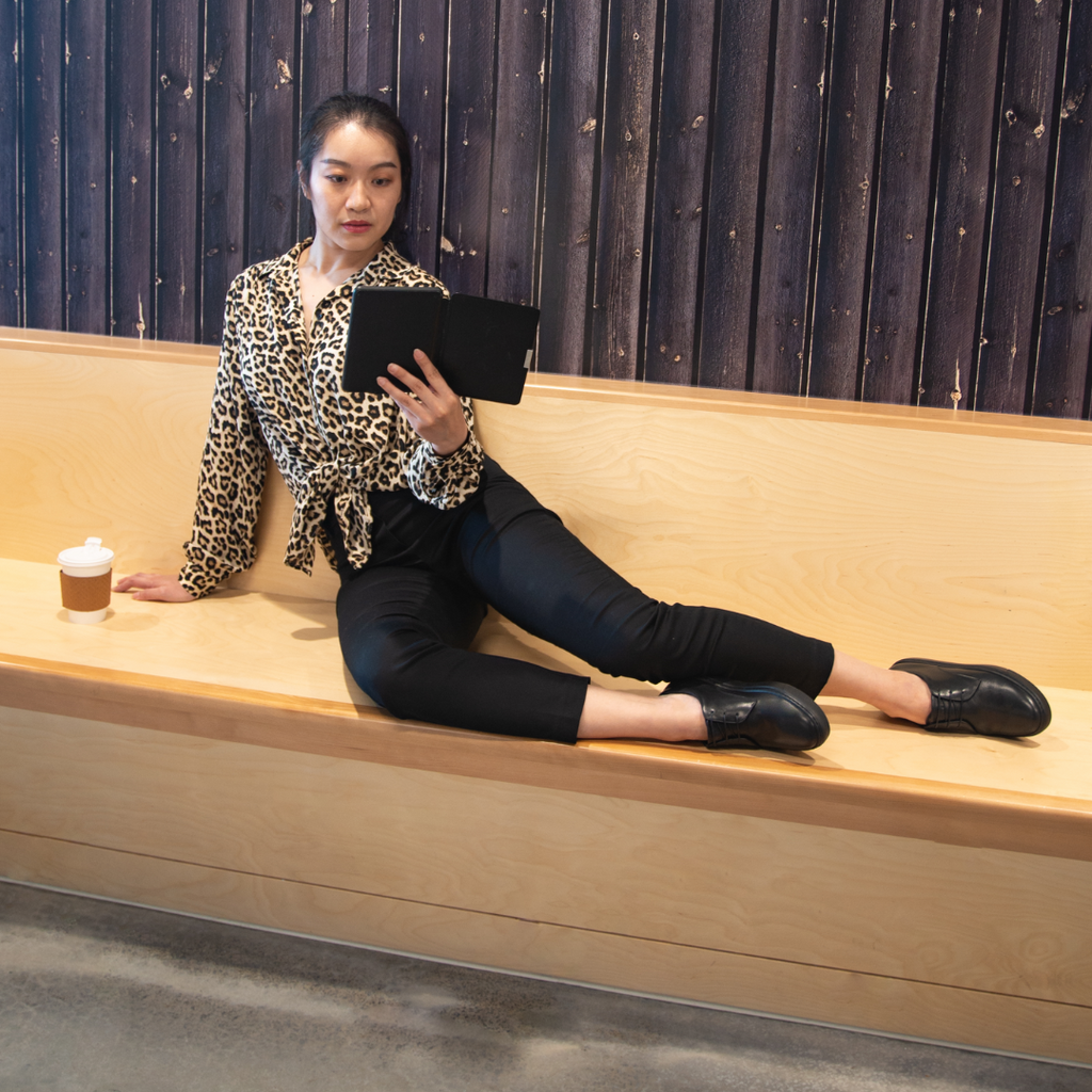 Black oxfords on seated legs; lace-up design with rubber sole visible.