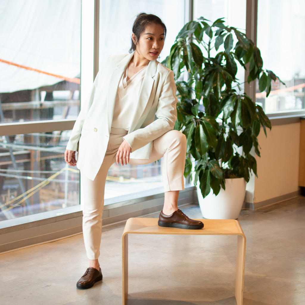 Brown lace-up dress shoes worn with pants in a seated office look