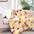 Yellow floral quilted throw blanket with scalloped edges and hummingbird print