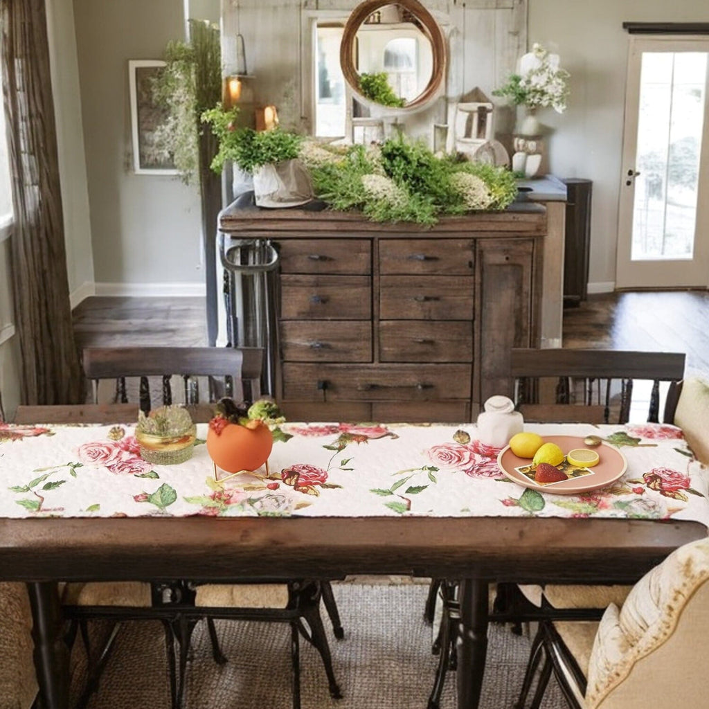 White quilted dining table runner with scattered pink roses and leafy accents.