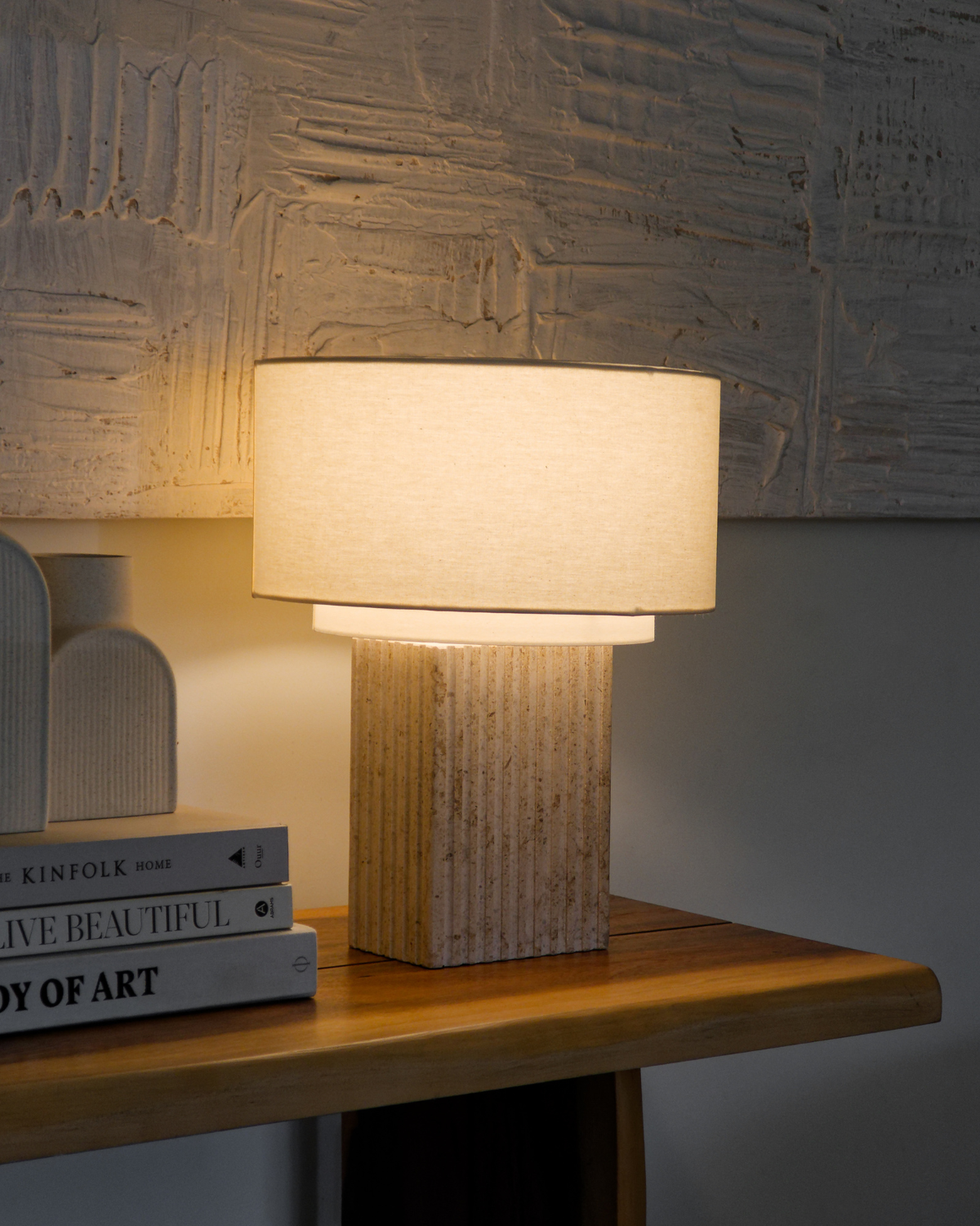 Table lamp with warm off-white shade on ribbed tan column base