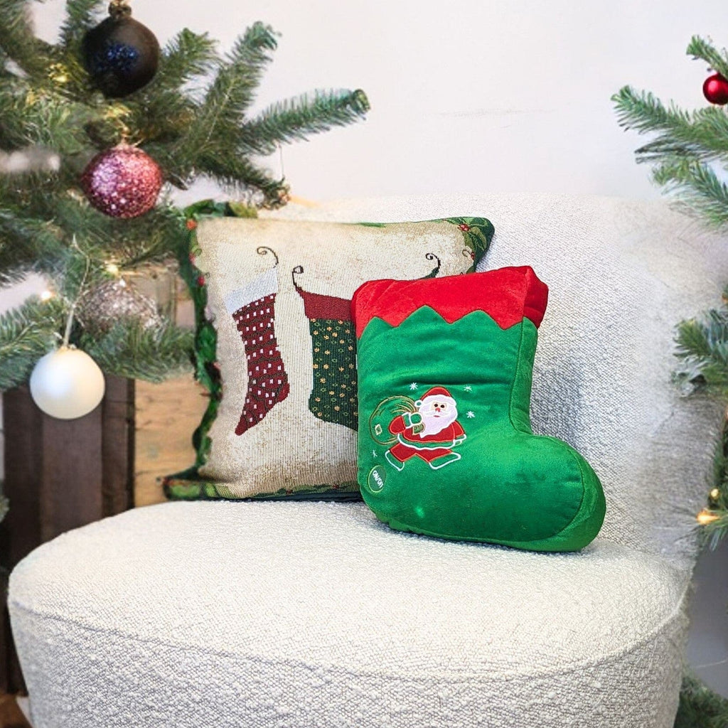 Green LED Christmas stocking pillow with Santa applique resting near holiday decor