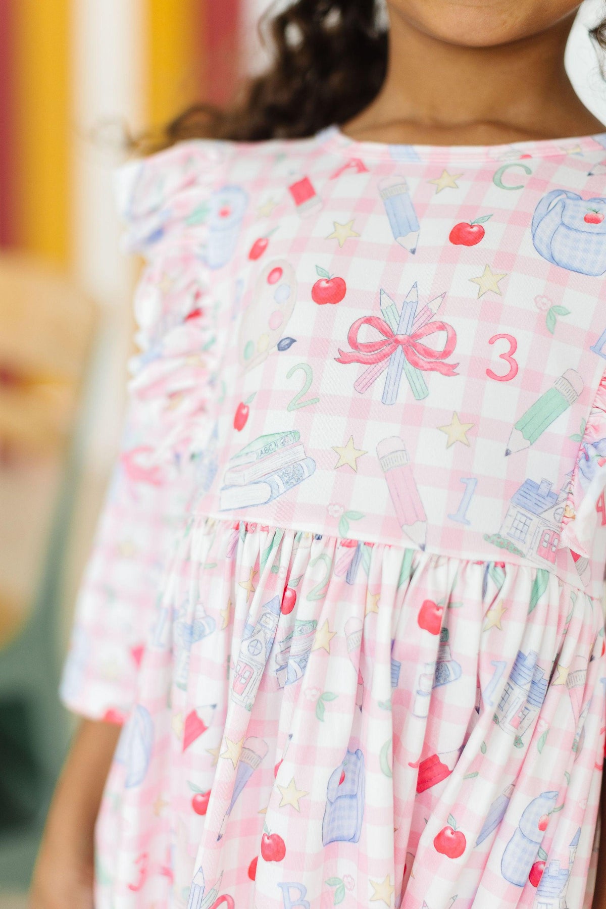 Close-up of white printed 3/4 sleeve ruffle twirl dress with bow graphic at chest