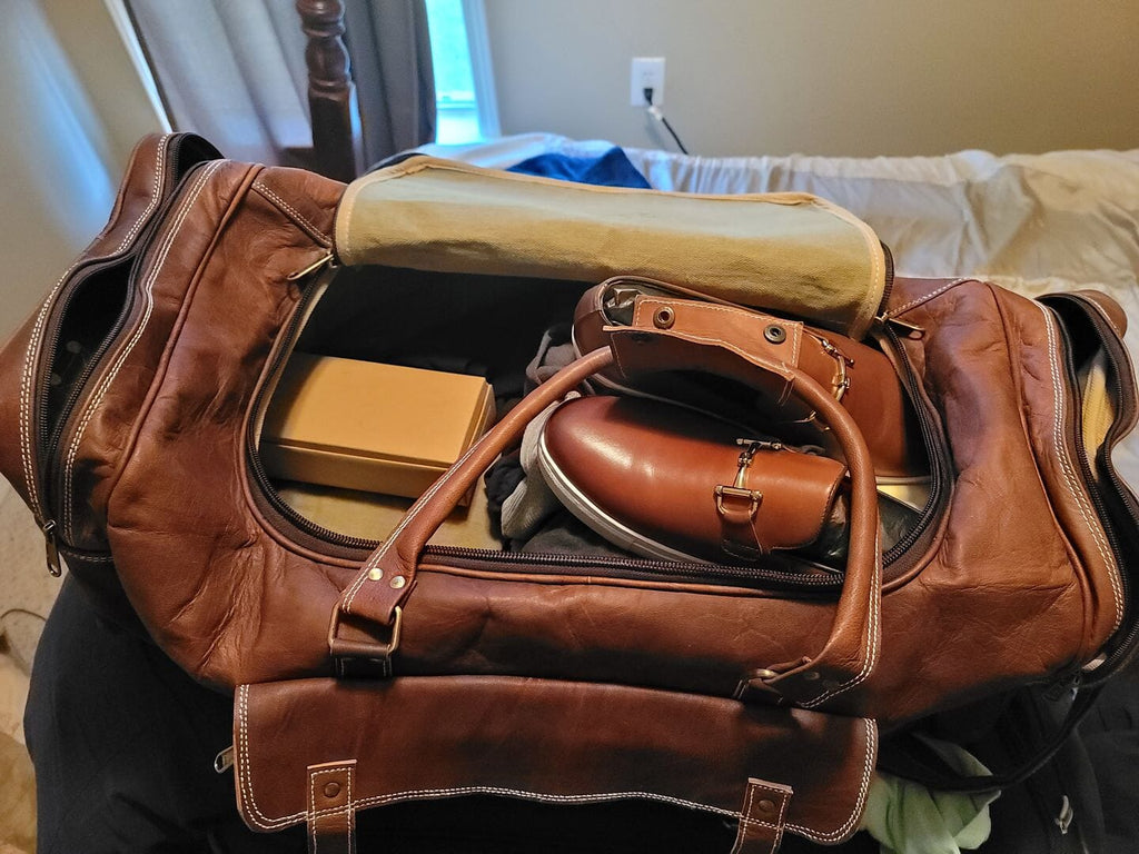 Brown leather duffle with open top showing interior organizers and zippered compartments