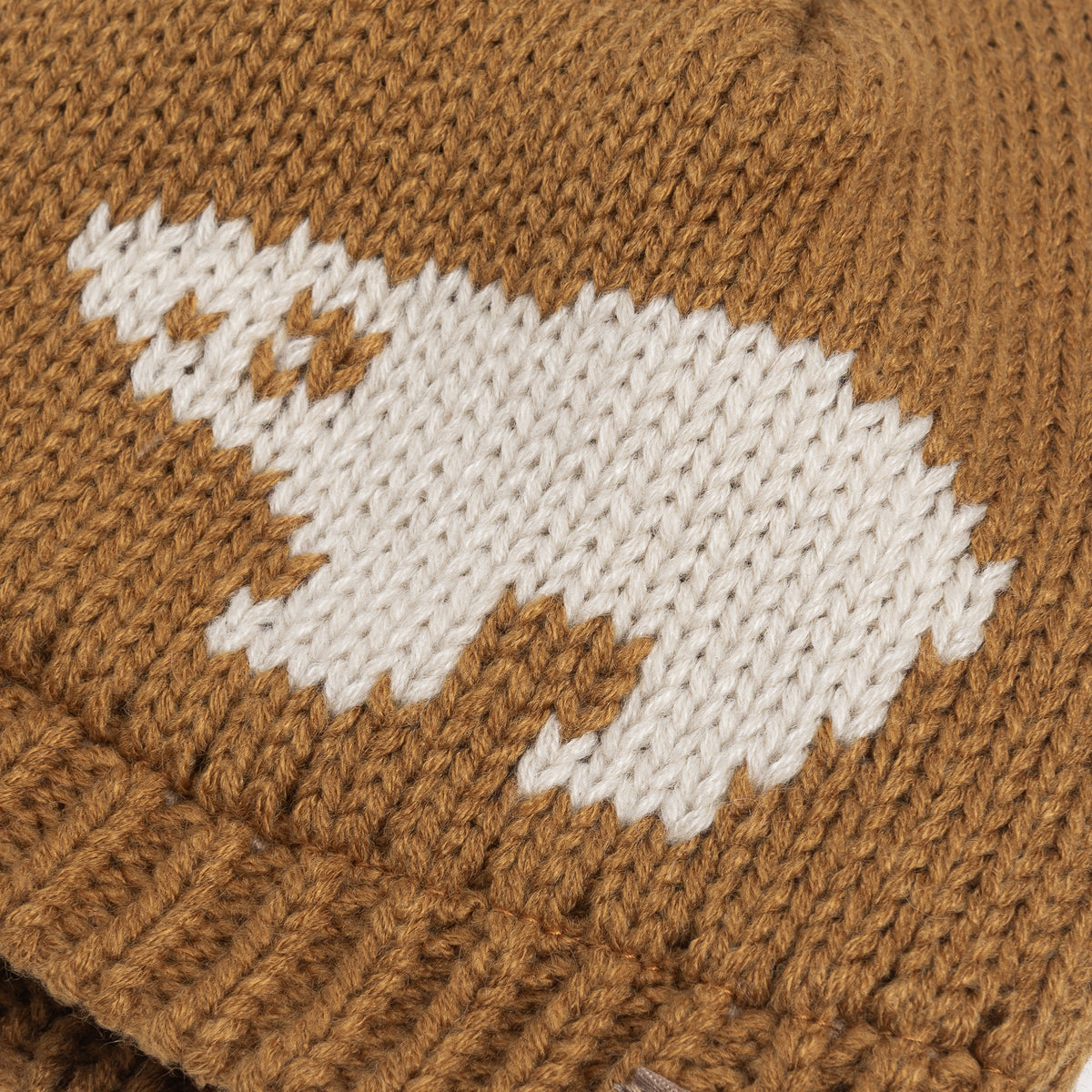 Brown knit beanie close-up with white and tan animal intarsia patch