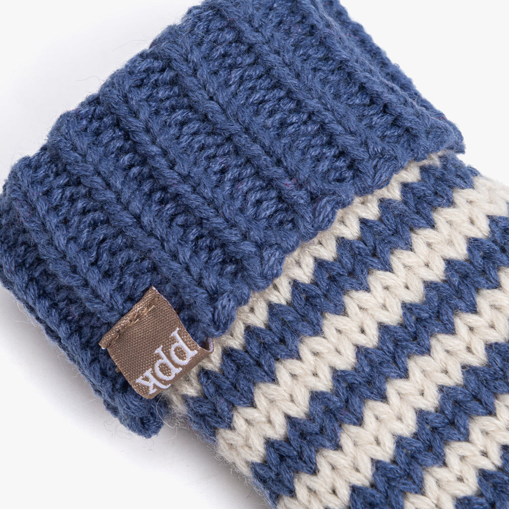 Close-up of blue striped knit mitten cuff with brown leather brand label