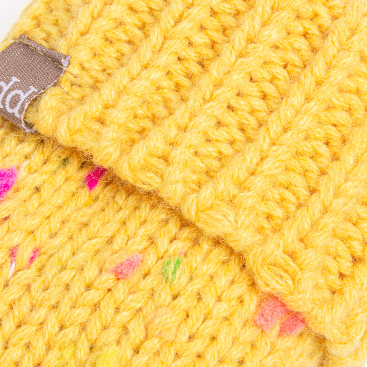 Close-up of yellow speckled knit mitten fabric with multicolor dot flecks and textured weave.