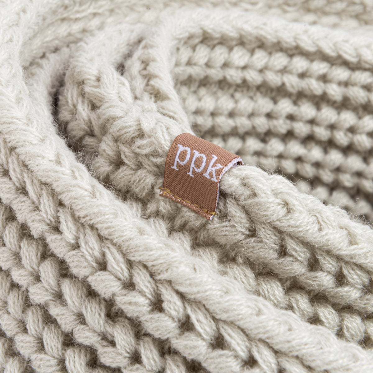Chunky knit infinity scarf close-up with brand patch and heather grey yarn
