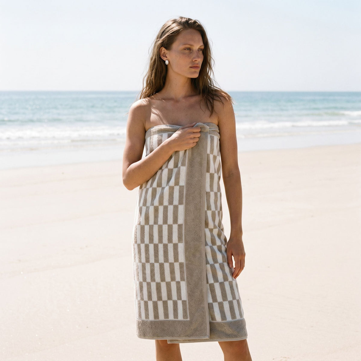 Cotton beach towel with gray-and-cream check pattern wrapped around a person.