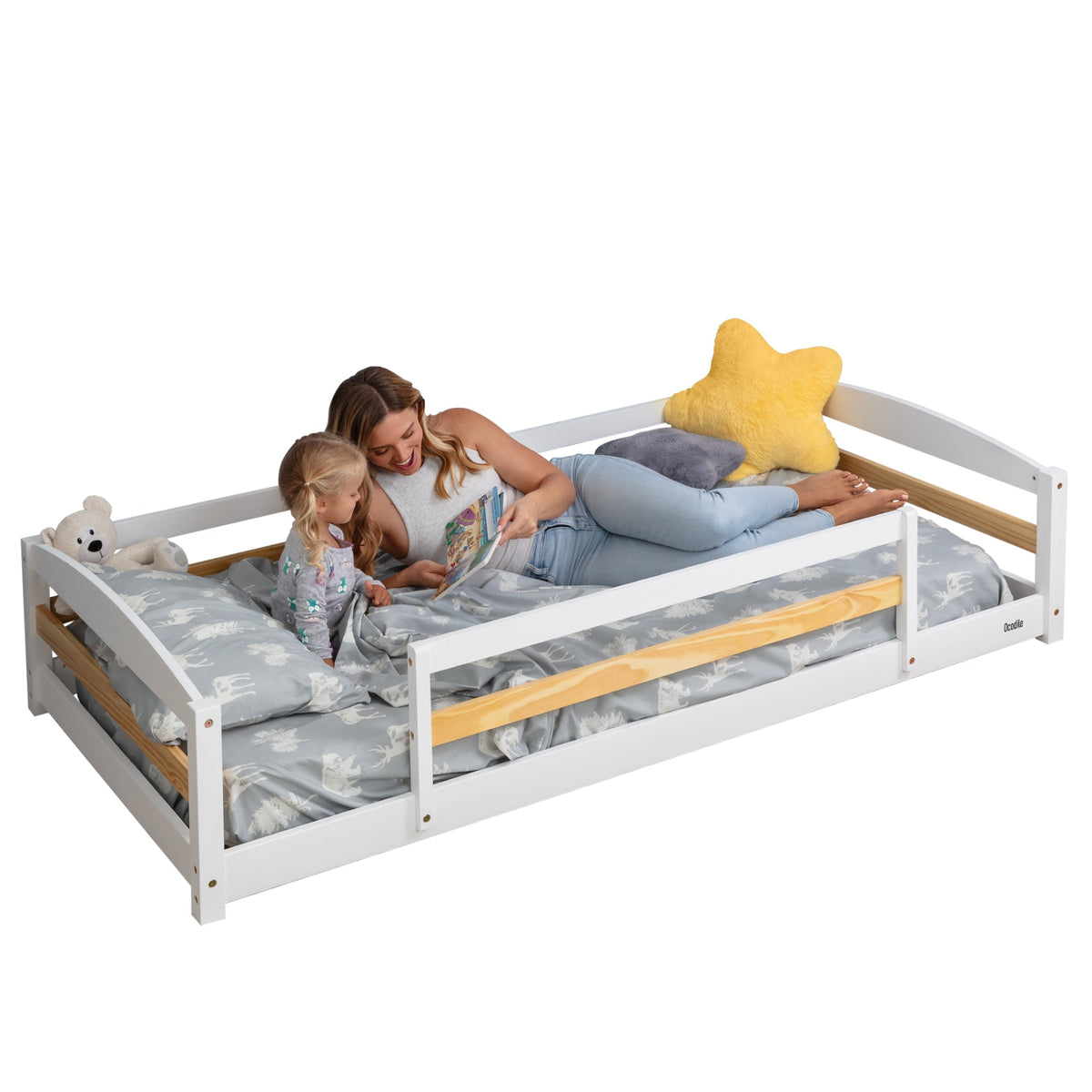 Twin floor bed with safety guardrails, gray frame and star pillow on patterned bedding
