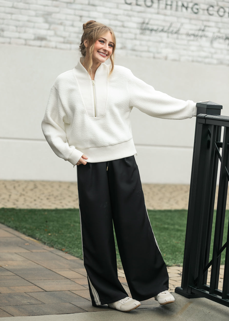 Nina wide-leg track pants, dark with white side stripe and relaxed straight legs.