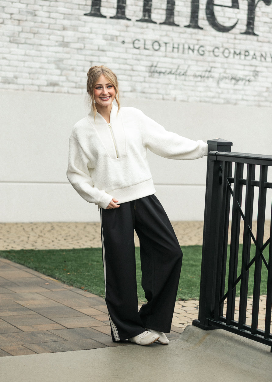 Nina wide-leg track pants in dark color with white side stripe and drawstring waist.