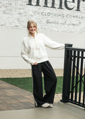 Nina wide-leg track pants in dark color with white side stripe and drawstring waist.