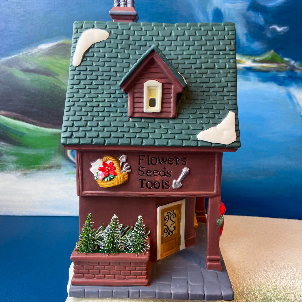 Porcelain garden shop house front with sign reading "Flowers Seeds Tools" and window